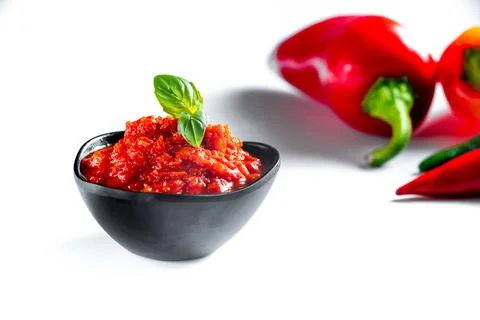 Red paste ajvar of red sweet peppers. on white background with ingredients for 库存照片