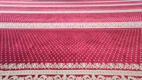 Red patterned prayer carpet covering a mosque floor Stock Photos