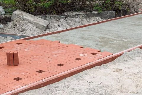 Red paving bricks form new sidewalk section on compacted base, with alignment Foto stock