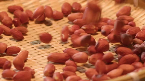 Red Peanuts Falling onto Woven Bamboo Mat Texture Close-up Stockbeeldmateriaal 335498425