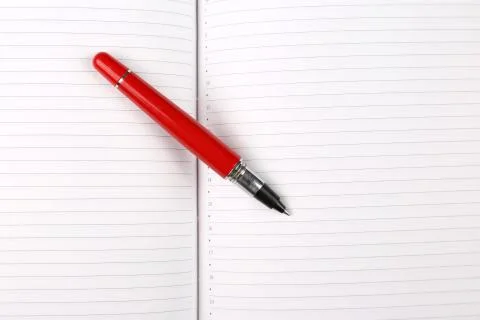 Red pen lying on an open notebook. Stock Photos