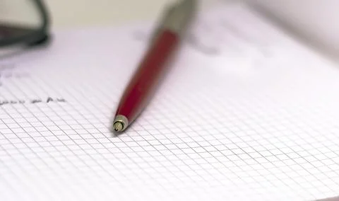 Red pen on an open squared notebook. Stock Photos