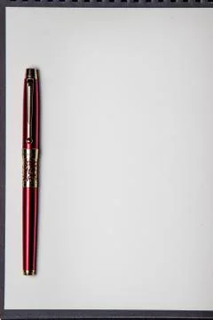 The red pen rests on a blank notebook.  Stock Photos