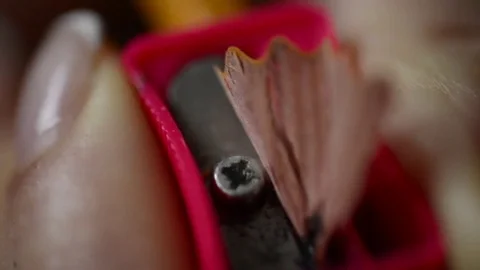Red pencil sharpener in a woman's hand sharpening a pencil, macro Stock Footage