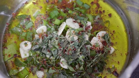 Red pepper being added into a pot with a garlicky oil sauce Stock Footage 84554715