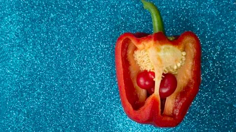 Red pepper cut in half with small paprika inside, blue glitter background. Foto stock
