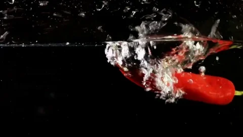 Red pepper falling into water super slow motion shot against black background Vídeos de archivo 75289895