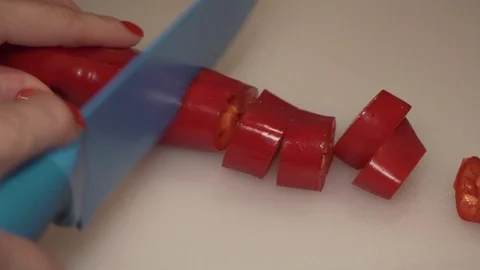 A red pepper (paprika) being cut with a knife by a woman's hand Stock Footage 84238420