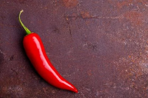 Red pepper pod on a rusty brown metal background. Stock Photos