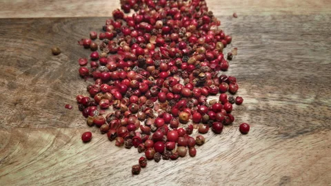 Red peppercorns in the foreground on a kitchen table Stock Footage 233209421