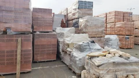 Red perforated bricks with rectangular holes on wooden pallets in an open-air Foto stock