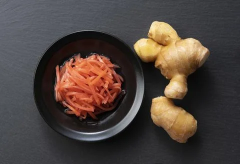 Red pickled ginger placed on a black background Stock Photos