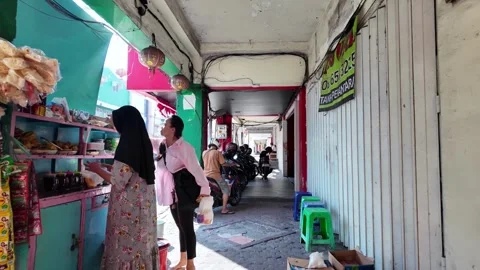 Red pillar frames bustling alleyway behind shop Vidéo 345154592