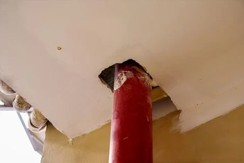 Red pillar supporting a ceiling with an exposed unfinished hole Stock Photos