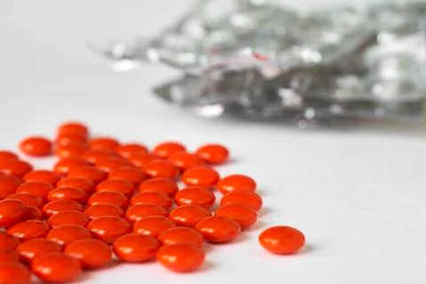 Red pills lying on white table with empty blister packs 写真素材