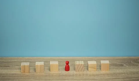 Red pin between brown cubic on the brown table and blue background Stock Photos