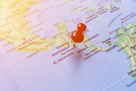 Red pin embroidered on the world map of El Salvador. Stock Photos