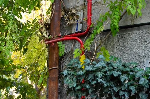 A red pipe is attached to a building Stock Photos