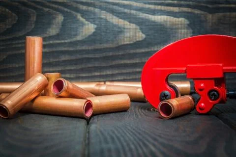 Red pipe cutter and copper pipes with connectors for plumbing repairs on blac Stock Photos
