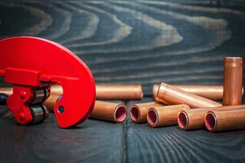 Red pipe cutter and copper pipes with connectors for plumbing repairs on blac Stock Photos