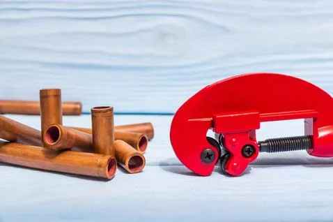 Red pipe cutter and copper pipes with connectors for plumbing repairs Stock Photos