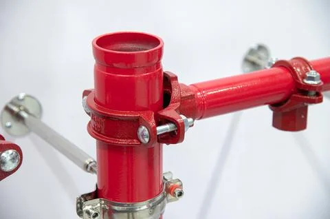 A red pipe with a silver bracket is attached to a wall Stock Photos