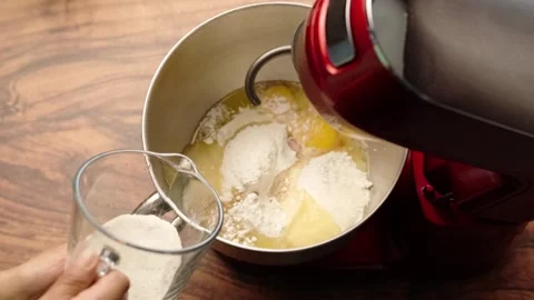 Red planetary mixer, adding yeast with a glass measuring cup Stock Footage 281459853