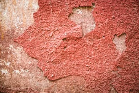 Red plaster partially peeling off of a wall Stock Photos