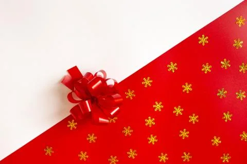 Red plastic bow on a red and white diagonal paper texture with golden snowflakes Stock Photos