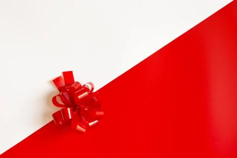 Red plastic bow on a red and white diagonal paper texture Stock Photos
