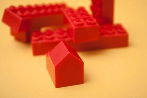 Red plastic bricks construction on yellow background Stock Photos