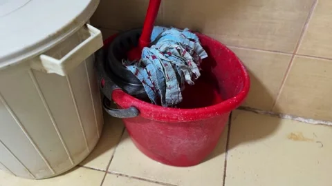 Red Plastic Bucket with Mop Rags Stored in Bathroom Corner on Tiled Floor Stock Footage 330925622