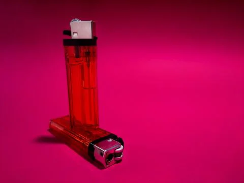 Red plastic cigarette lighter on red paper background Stock Photos