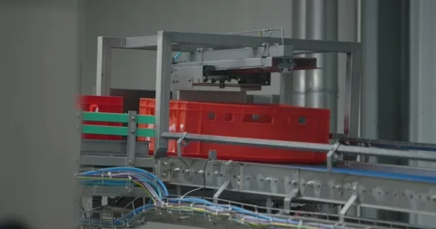 Red plastic crate moving along an automated conveyor system inside a bright Stock Footage 340002480