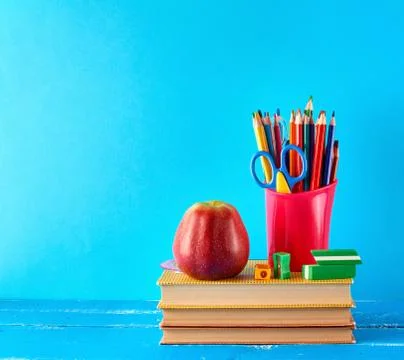 Red plastic cup with multi-colored wooden pencils stands on a stack of books Stock Photos