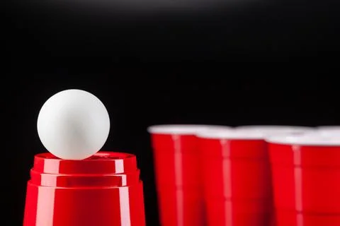 Red plastic cups and ball for game of beer pong Stock Photos