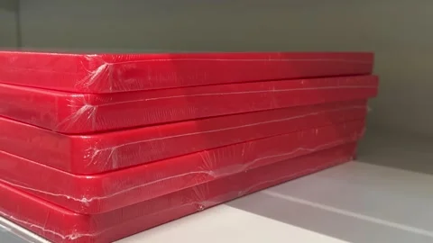 Red plastic cutting boards stacked on retail shelves in a kitchenware store Stock Footage 345173918