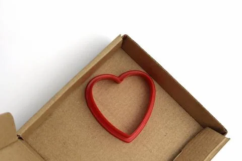 Red plastic heart and cardboard box. Romance, love card. Copy space - concept Stock Photos