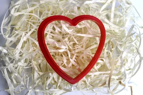 Red plastic heart shape and natural filler. Romantic, love card. Copy space - Stock Photos