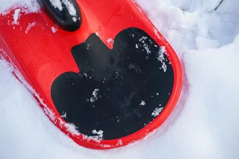 Red Plastic Sled Close-Up on Snow Background Winter Outdoor Activity Foto stock