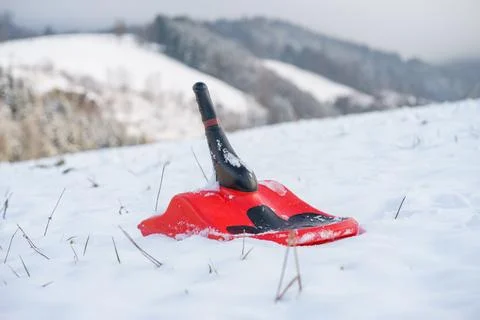 Red Plastic Snow Sled Lying on White Snow in Winter Outdoor Scene Stock Photos
