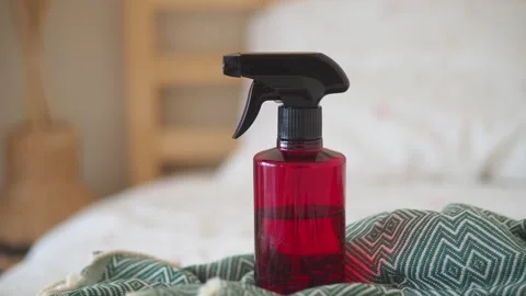 A red plastic spray bottle with a black trigger is on a green blanket in mo.. Stock Footage 332105585