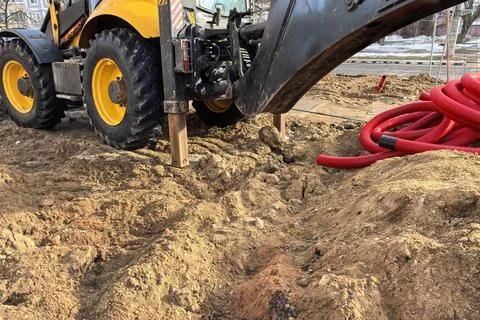 Red plastic tubes coiled on construction site during afternoon work near busy Foto stock