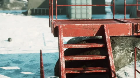 Red platform in a snowy environment near industrial structures Stock Footage 344166663