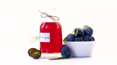 Red plum syrup in bottle with fresh plums on white background Stock Footage 344168083