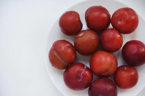Red plums on a white background.  Plums on a plate. Washed fruits. Stock Photos