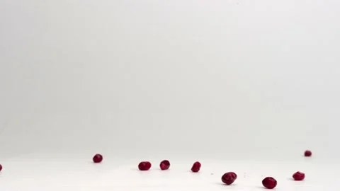 Red pomegranate arils falling onto white studio backdrop and bouncing in Stock Footage 234183358
