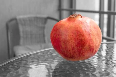 Red pomegranate on a glass table, monochrome. Stock Photos