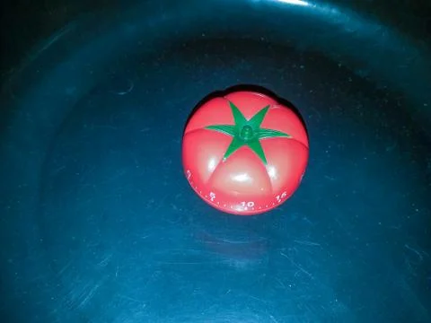 Red pomodoro timer in tomato shape on a black texture background. Stock Photos