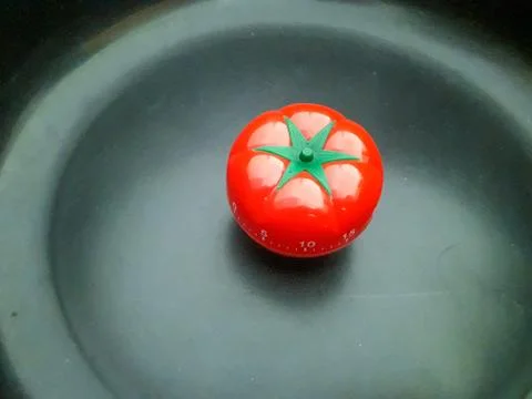Red pomodoro timer in tomato shape on a black texture background. Stockfoto's